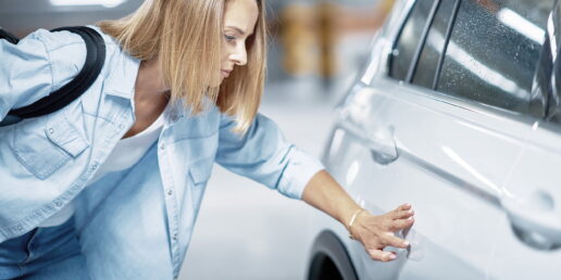 Eine junge Frau mit zerkratztem Auto