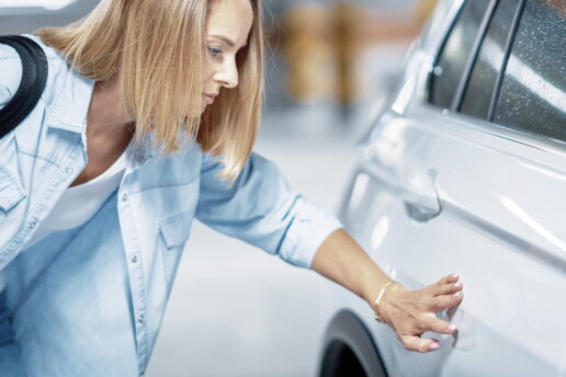 Eine junge Frau mit zerkratztem Auto