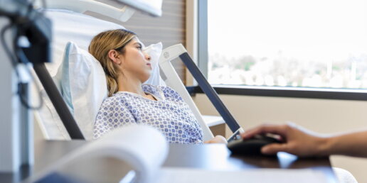 Die Patientin liegt im Krankenhausbett und schaut aus dem Fenster