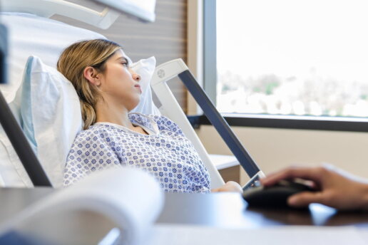 Die Patientin liegt im Krankenhausbett und schaut aus dem Fenster