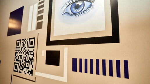 An der Wand ist ein Auge, ein QR-Code und weitere Forme